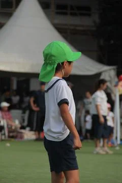 Child wearing green cap standing on grass field Stock Photos