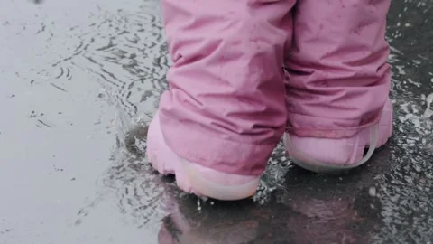 Child wearing pink boots playing outdoors. Little girl in vibrant rain boots cre Stock Footage 334551189