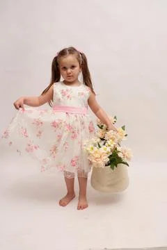 A child on a white background in an elegant light dress. Little girl with a Stock Photos
