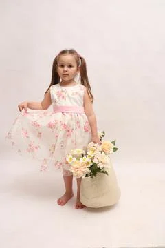 A child on a white background in an elegant light dress. Little girl with a Stock Photos