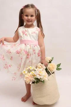 A child on a white background in an elegant light dress. Little girl with a Stock Photos