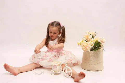 A child on a white background in an elegant light dress. Little girl with a Stock Photos