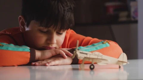 Child will put his head in his hands and look at wooden model of the aircraft Stock Footage 88438486