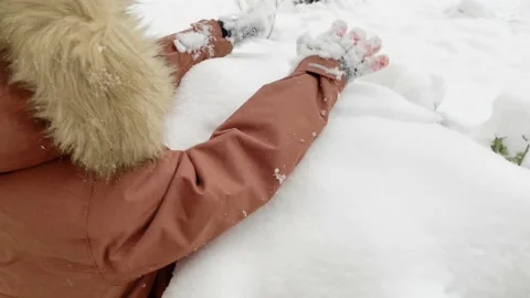 A child in winter clothes clears snow from bushes, Joy of the first snow Stock Footage 145615276