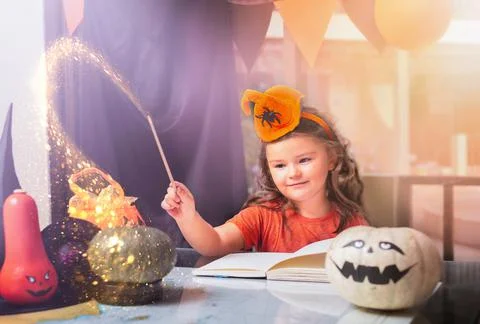 Child on witch costume make magic over Halloween pumpkins Stock Photos