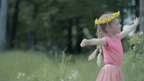 Child without front teeth smiles and whirls, a wreath of dandelions on his head Stock Footage 89984224