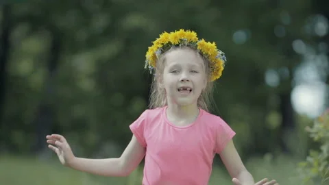 Child without front teeth smiles and sings a song on the head of a wreath of Stock Footage 89984595