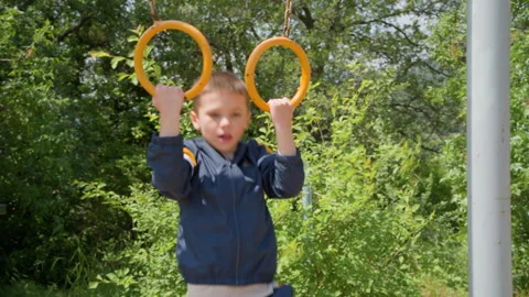Child Working Out on Yellow Rings at Outdoor Training Area Stock Footage 328635658