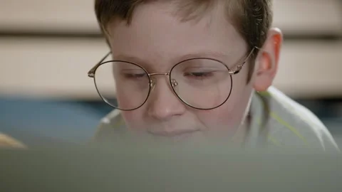 Child works at computer. Close-up of boy face in big glasses who looks at laptop Видео 307170641