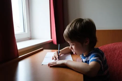 The child writes down the answer to the solution of the example in a copybo.. Stock Photos