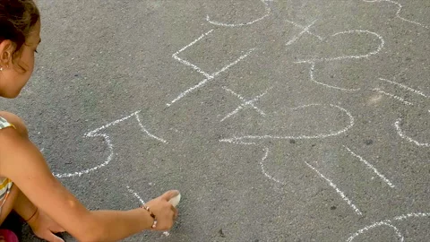 The child writes equations on the asphalt. Selective focus. Stock Footage 157481710