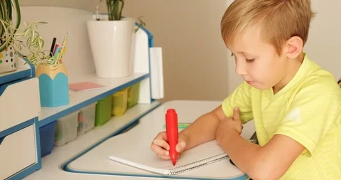 Child writes the letters in school notebook. Schoolboy is doing  homework at  Stock Footage 119527350