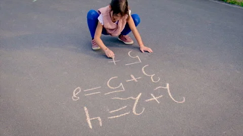 The child writes math on the pavement. Selective focus. Stock Footage 154997978