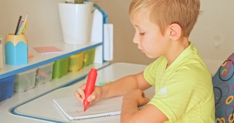 Child writes the numbers in school notebook. Schoolboy doing  homework at hom Stock Footage 121062312