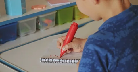 Child writes the numbers in school notebook. Schoolboy doing  homework at hom Video stock 127644356