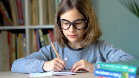 The child writes a solution to the problem in a notebook. An emotional look in Stock Footage 126059425