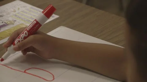 Child writing lowercase d with red marker on small whiteboard 库存影片 304372771