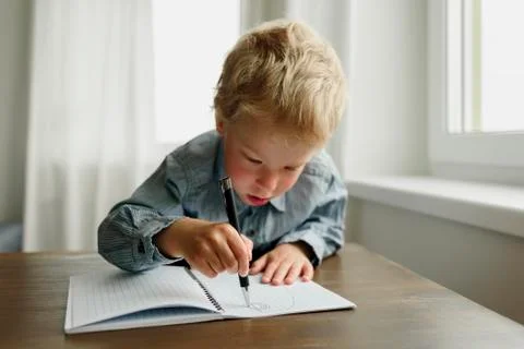 Child writing by right hand in notepad Stock Photos
