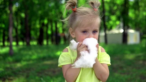 A child in a yellow t-shirt eats cotton candy on a sunny summer day. Stock Footage 200976459