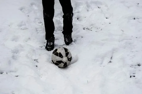 Child&amp;#39;s legs and soccer ball on snow background Stock Photos