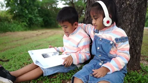 Childen sitting in the park studying Stockbeeldmateriaal 221698545
