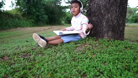 Childen sitting in the park studying Stock Footage 221702955