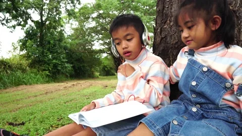 Childen sitting in the park studying Stock Footage 221703533