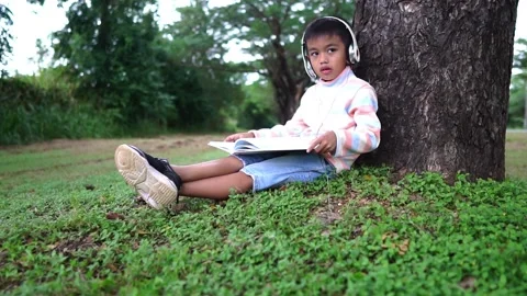 Childen sitting in the park studying Stockbeeldmateriaal 221703900