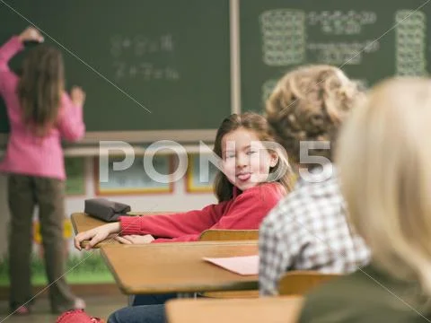 Children (4-7) in class room, focus on girl sticking out tongue Stock Photos