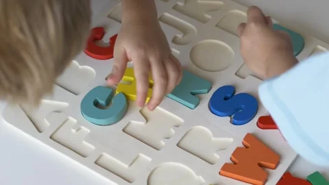 Children actively participate in assembling a vibrant alphabet puzzle on a white Video stock 318294025