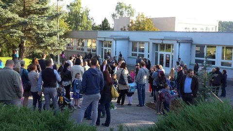 Children and adults stand in front of a school on the first day of first grade Stock Footage