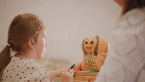 Children and parent creating festive pumpkin art in bright kitchen. Family Stock Footage 346390915