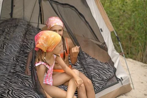 The children are cheerfully chatting while sitting in the tent at the camping Stock Photos