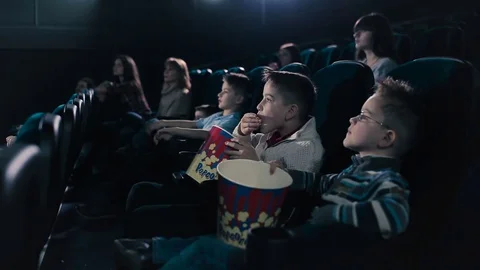 The children are eating popcorn in the cinema Stock Footage