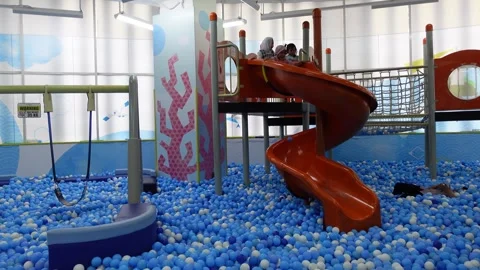 Children are happily playing on a slide in a pool filled with balls, ball poo Stock Footage 314269871