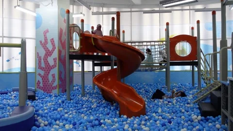 Children are happily playing on a slide in a pool filled with balls, ball poo Stock Footage 314269992