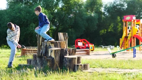 Children are joyfully playing on log stumps at a lively and engaging playground Stock Footage 314747394