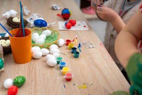 Children are joyfully preparing for Easter by painting eggs in a cozy room Stock Photos