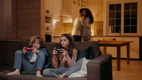 Children are playing on game console, parents are dancing at the background Видео 165412428