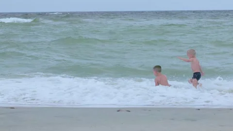 Children are playing joyfully and happily by the ocean waves, enjoying their 库存影片 315864147