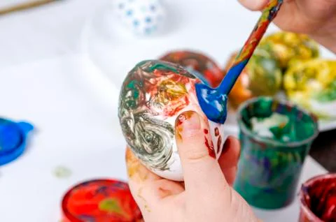 Children are preparing for Easter. Coloring eggs with brushes and multi-color Stock Photos