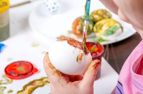 Children are preparing for Easter. Coloring eggs with brushes and multi-color Stock Photos