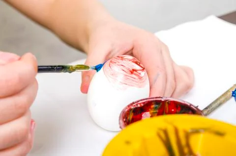 Children are preparing for Easter. Coloring eggs with brushes and multi-color Stock Photos