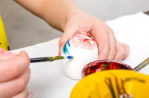 Children are preparing for Easter. Coloring eggs with brushes and multi-color Stock Photos