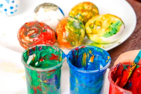 Children are preparing for Easter. Coloring eggs with brushes and multi-color Stock Photos