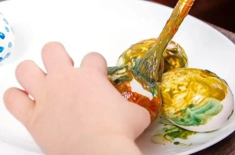 Children are preparing for Easter. Coloring eggs with brushes and multi-color Stock Photos