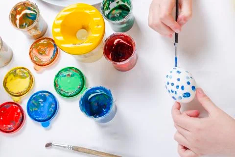 Children are preparing for Easter. Coloring eggs with brushes and multi-color Stock Photos