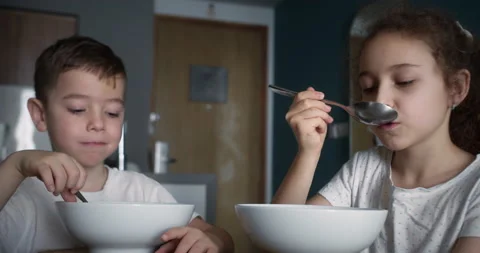 Children are sitting at the kitchen table having breakfast and eating oatmeal Stock Footage 220305830