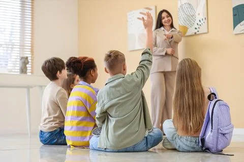 Children asking question to guide at exhibition in modern art gallery, back v Stock Photos