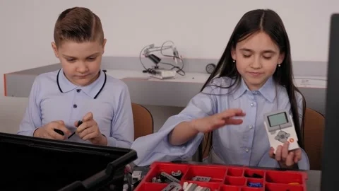 Children assembling a robot from plastic parts programmed on a computer. 库存影片 150442197